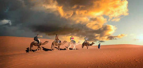アフリカのモロッコのメルズーガ近くのサハラ砂漠のエルグ チェビ砂丘の上に素晴らしい夕日 素晴らしい空と美しい砂の風景 砂丘を通って行く人々のラクダキャラバン マロック — ストック写真