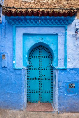 Tipik, eski, karmaşık bir şekilde oyulmuş, çivili, Faslı kapı ve çerçeve ve CheFCHAOUEN, Fas 'taki eski ev. Medine 'deki mavi şehrin güzel manzarası. boyanmış evler