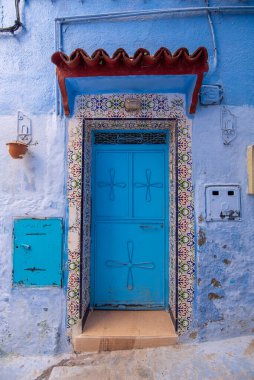 Tipik, eski, karmaşık bir şekilde oyulmuş, çivili, Faslı kapı ve çerçeve ve CheFCHAOUEN, Fas 'taki eski ev. Medine 'deki mavi şehrin güzel manzarası. boyanmış evler