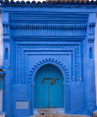 Tipik, eski, karmaşık bir şekilde oyulmuş, çivili, Faslı kapı ve çerçeve ve CheFCHAOUEN, Fas 'taki eski ev. Medine 'deki mavi şehrin güzel manzarası. boyanmış evler