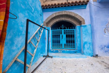 Mavi şehrin güzel manzarası CheFCHAOUEN, Medina 'daki MoroCCO. Geleneksel Fas mimari detayları ve boyalı evler. Kapısı olan bir sokak ve kemerli parlak mavi duvarlar