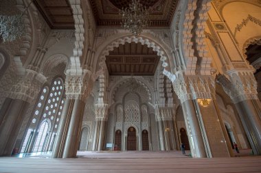 Casablanca, Morocco - 03.02.2020: Hassan II Mosque interior corridor with columns. Arabic arches, ornaments, chandelier and lighting. It is the largest mosque in Maroc. clipart