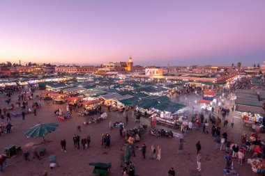Marakeş, Fas - 22 Kasım 2019: İnsanlar gün batımında ünlü Meydan ve pazar yerini (Jemaa el Fnaa) ziyaret eder. Marakeş Medine 'deki meydan UNESCO Dünya Mirası' nın bir parçası.