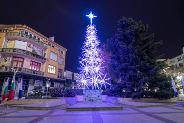 Burgaz, Bulgaristan - 08 Aralık 2019. Burgaz şehrinde gece yılbaşı ışıkları süslemesi. Kasabanın Troikata meydanındaki güzel ışıklandırılmış kostüm ağacı. Alexandrovska Caddesi