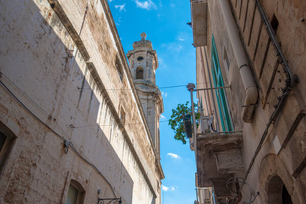 Street and alley with a view to the bell tower of Church of Saint Joseph and Anna (Chiesa dei Santi Giuseppe e Anna) in the old town of Monopoli, Puglia, Italy. A region of Apulia