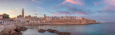 Başkent Bari 'de ve Apulia (Puglia) bölgesinde Monopoli limanının günbatımı manzarası ve güzel aydınlatılmış katedral Bazilikası Maria Santissima della Madia