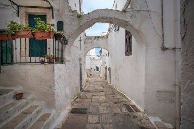 Ostuni, Puglia, İtalya - 15.02.2020: Eski kentin sokak manzarası - Brindisi ili, Apulia bölgesi. Eski tarihi merkezde geleneksel beyaz yıkamalı evler resim kadar dar.