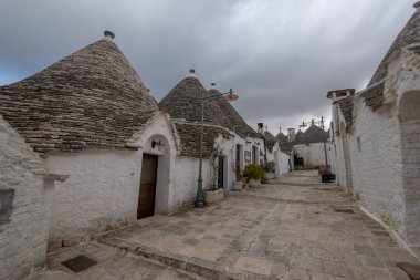 ALBEROBELLO, PUGLIA, ITALY - 14 Mart 2019: Itria Vadisi, Apulia, Güney İtalya 'nın karakteristik koni çatılı beyaz evleri Alberobello' nun ünlü Trulli manzarası. 