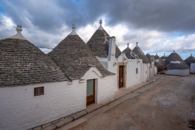ALBEROBELLO, PUGLIA, ITALY - 14 Mart 2019: Itria Vadisi, Apulia, Güney İtalya 'nın karakteristik koni çatılı beyaz evleri Alberobello' nun ünlü Trulli manzarası. 