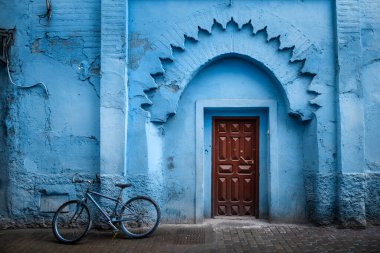 Geleneksel Fas antik ahşap giriş kapısı. Chefchaouen, Fas 'taki eski Medine' de. Tipik, eski, mavi, karmakarışık oyulmuş, çivili, Fas riad kapısı.