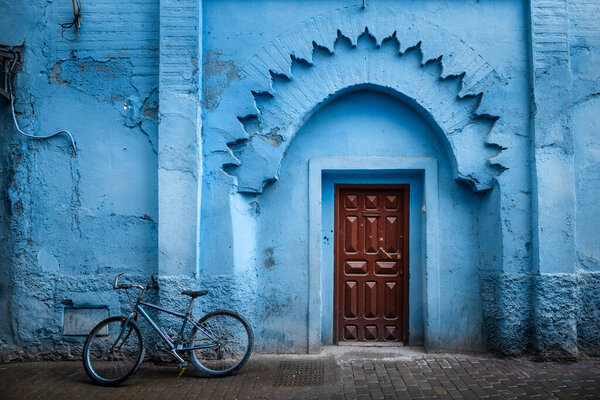Traditional Moroccan ancient wooden entry door. In the old Medina in Chefchaouen, Morocco. Typical, old, blue intricately carved, studded, Moroccan riad door.