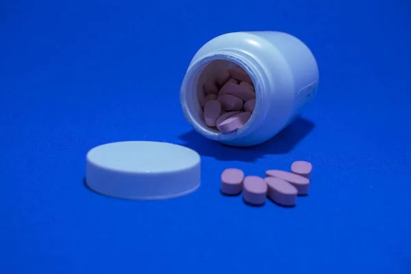 medicines pills pink in a white jar scattered on the table