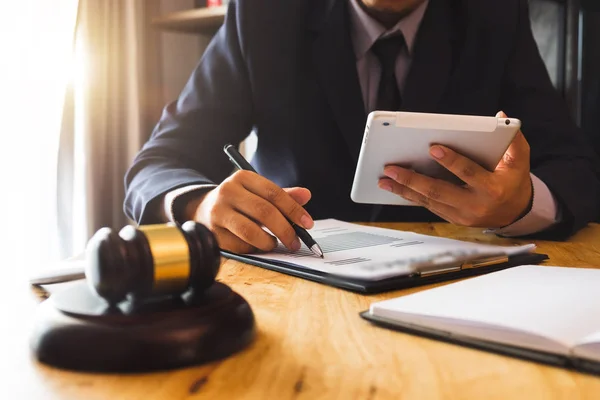 justice and law concept.Male judge in a courtroom  the gavel, working with digital tablet computer on wood table in morning light