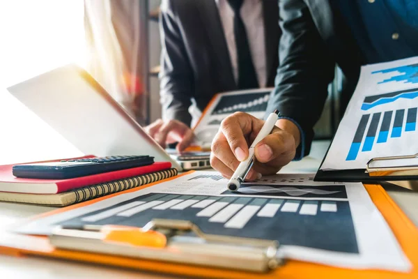 business documents on office table with smart phone and digital tablet and graph business with social network diagram and two colleagues discussing data working in the office