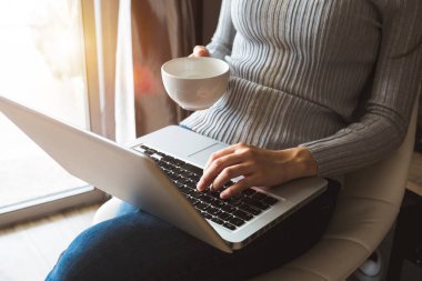 dizüstü bilgisayar kullanarak ve yazarak ve kahve fincanı kafe, ev ofis gün ışığına tutarak womman