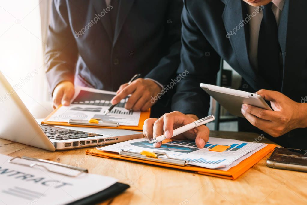 business documents on office table with smart phone and digital tablet and graph business with social network diagram and two colleagues discussing data working in the office