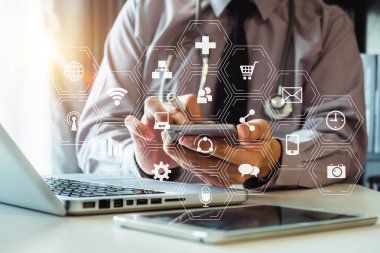 Tıbbi teknoloji konsepti. Doktor cep telefonu, steteskop ve dijital tablet dizüstü bilgisayarla sabah saatlerinde modern hastanede çalışıyor.