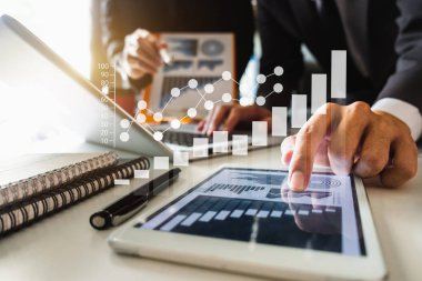 Ofis masasında akıllı telefon ve hesap makinesi olan iş belgeleri dijital tablet ve sosyal ağ diyagramı olan grafik işleri ve ofiste çalışan iki iş arkadaşı