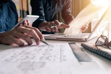 Çalışma ve tablet hakkında konuşan iki meslektaş, ofisteki inşaat sahasında mimari projeyle ilgili bilgisayarı açtılar.