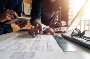 Çalışma ve tablet hakkında konuşan iki meslektaş, ofisteki inşaat sahasında mimari projeyle ilgili bilgisayarı açtılar.