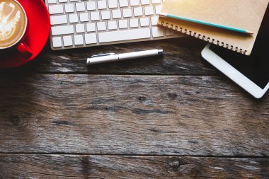 Ahşap ofis resepsiyon masa bir sürü şeyler tablet, dizüstü bilgisayar, smartphone, Not defteri ve kahve Kupası Not defteri. Kopya alanı ile üstten görünüm.