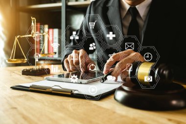 Adalet ve hukuk kavramı. Bir mahkeme salonunda, tokmak, akıllı telefon, dizüstü bilgisayar ve dijital tablet bilgisayarla sabah ışığı altında çalışan erkek yargıç. 