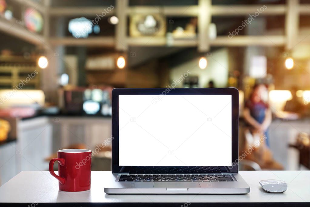 Front view of cup and laptop, smartphone, and tablet on table in office and background  in the coffee shop and restaurant