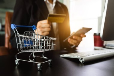 Online alışveriş sepeti kavramı. akıllı telefon, tablet ödemeler ve holding kredi kartı online alışveriş, omni kanal, bilgisayar sanal simgeler kullanarak iş kadını ele 
