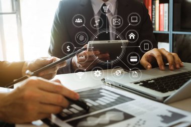 İş ortakları toplantısı konsepti. Ofiste bilgisayar, tablet ve akıllı telefon kullanan bir iş adamı. Sanal simge ekranında sabah ışığında dijital pazarlama mobil uygulaması