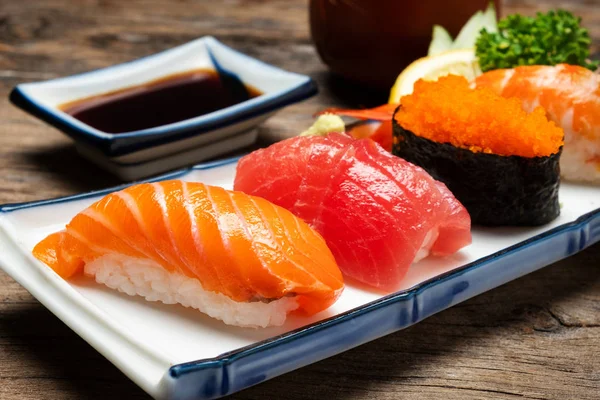 Suşi somon ve ton balığı suşi karides ve wasabi beyaz tabakta. siyah masaya