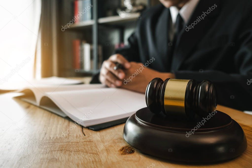 Justice and law concept.Male judge in a courtroom with the gavel, working with, digital tablet computer and smartphone docking keyboard, eyeglasses, on table in morning light