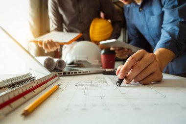 Çalışma ve tablet hakkında konuşan iki meslektaş, ofisteki inşaat sahasında mimari projeyle ilgili bilgisayarı açtılar.