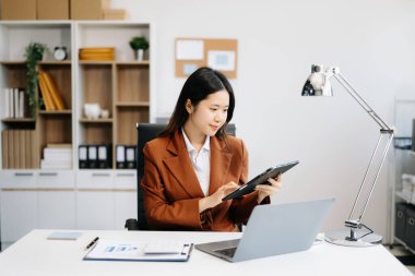 Ofis masasında tablet ve laptop kullanan bir iş kadını. Ofiste vergi, rapor, muhasebe, istatistik ve analitik araştırma kavramı 