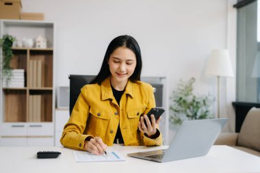 Başarılı Asyalı İş kadını Laptop 'ta Finans Analizi ve modern ofis masasında akıllı telefon kullanımı. vergi, rapor, muhasebe, istatistik ve analitik araştırma kavramı