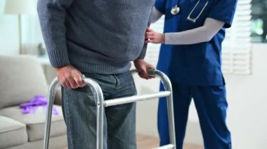 Hemşire yaşlı bir adama destek için Walker 'ı kullanıyor.