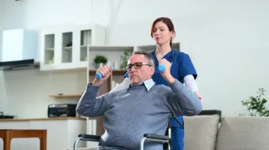 Tekerlekli sandalyede yardım eden kadın küçük ağırlıklar kaldırıyor.