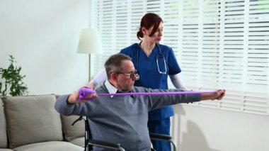 Kadın direnç bandı kullanarak erkeğin fizik tedavisine yardım ediyor.