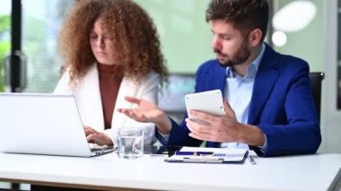 Dizüstü bilgisayarlar üzerinde çalışırken fikirleri tartışan iki meslektaş