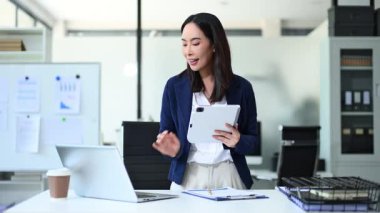 Modern ofiste konuşurken elinde tablet bulunan kadın yönetici.