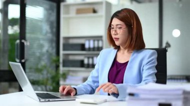 Modern ofis ortamında dizüstü bilgisayarda çalışan Asyalı iş kadını