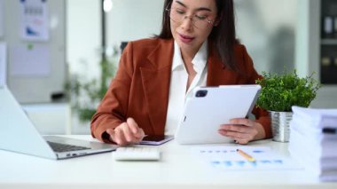 Masadaki harcamaları hesaplarken tablet kullanan kadın