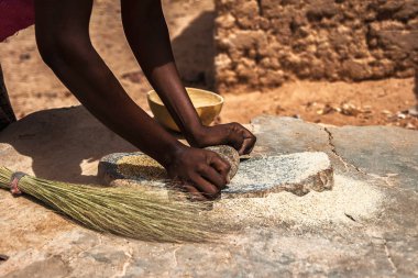 Geleneksel grindstones, Burkina Faso kullanarak un içine tahıl darı taşlama bir Afrikalı kadın.