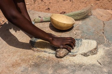 Geleneksel grindstones, Burkina Faso kullanarak un içine tahıl darı taşlama bir Afrikalı kadın.