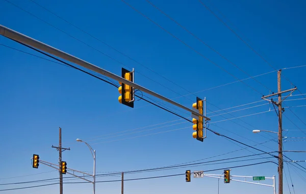Many traffic lights hanging over the road at a crossroad on a clear blue sky,  USA.