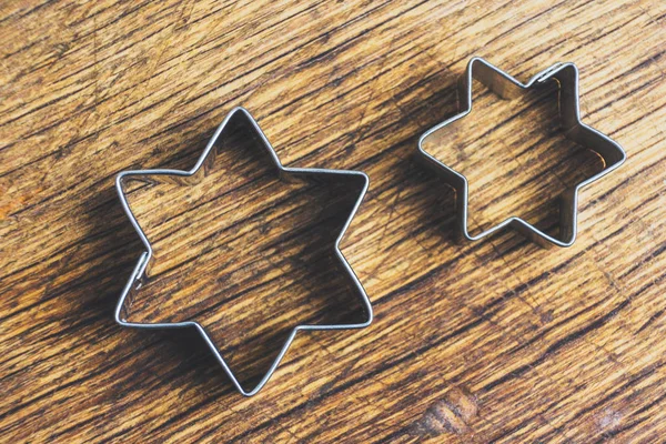 Two star shaped pastry cutters lying on a old wooden table. These pastry cutters are used to make traditional christmas cookies - Alsace, France