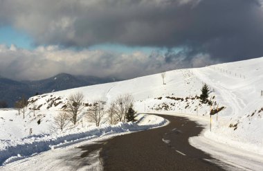 Vosges Dağları (Fransa) dramatik bir bulutlu gökyüzü - Aralık 2017 kışın karlı yol Eğrideki