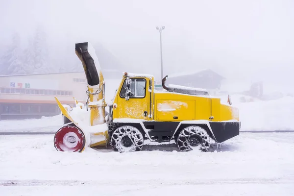 A yellow snowy and frozen snow plow in winter during a foggy day - - Vosges (France) - december 2017