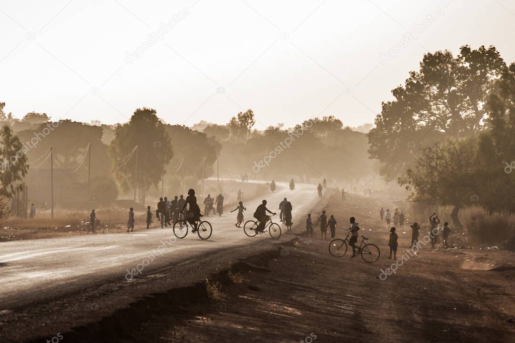 Highway at the exit of Ouagadougou, Burkina Faso, at dusk with silhouetted people. African scenery.