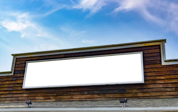 Große weiße Tafel an einer Holzfassade mit Himmel. Vorlage, Attrappe, Werbeanwendung. — Stockfoto