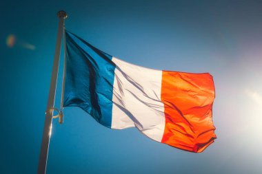 Güneş ışığı ile mavi bir gökyüzüne karşı güzel bir el sallayan Fransız bayrağı arıyorsunuz.